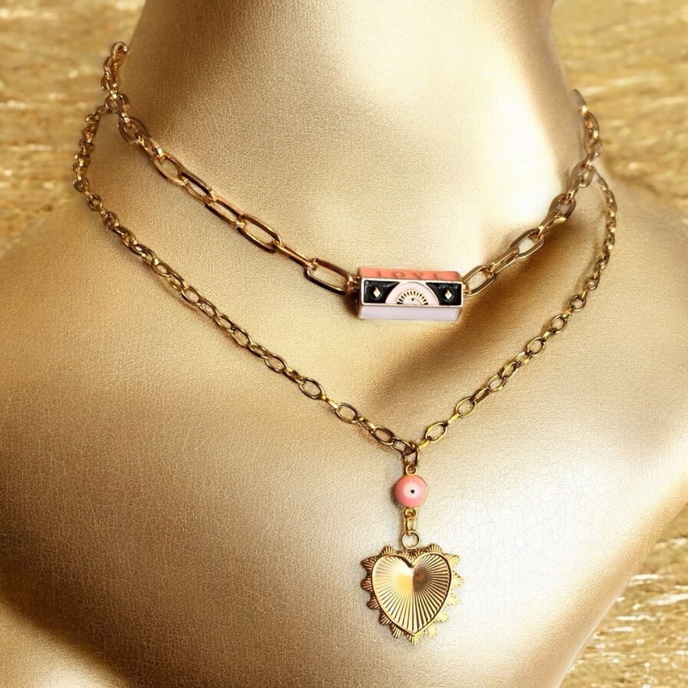 Gold toned chains with black, white, gold, and pastel pink enamel charms.